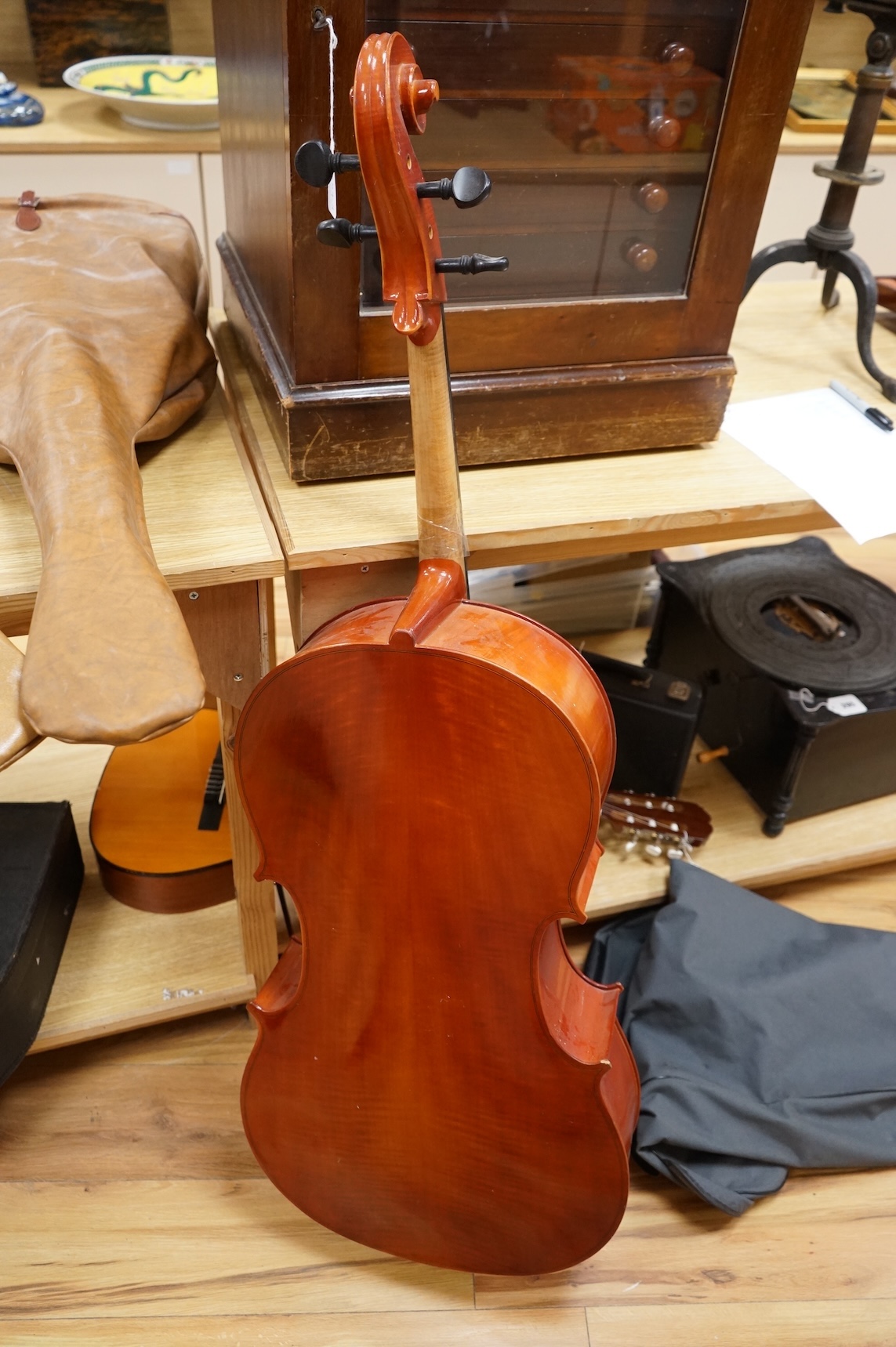 A modern student’s cello in a soft case and a student’s Spanish classical guitar